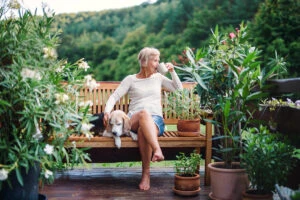 a woman sits on a bench with her dog drinking coffee